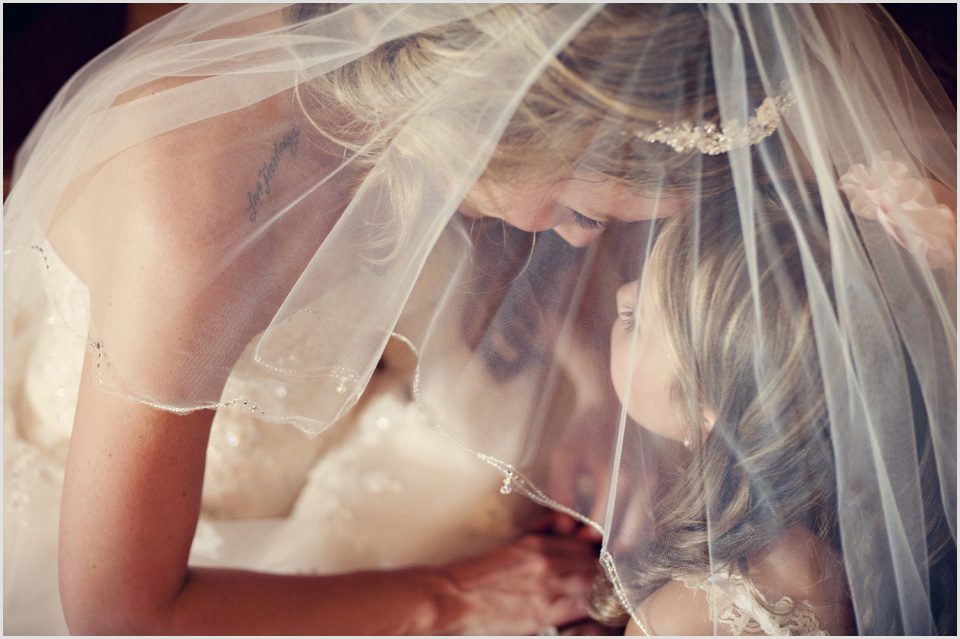 bride with her daughter the flower girl through wedding veil