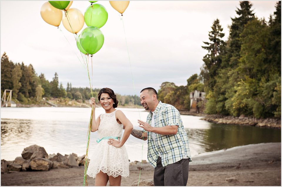 couple laughs while holding balloons during engagement photos