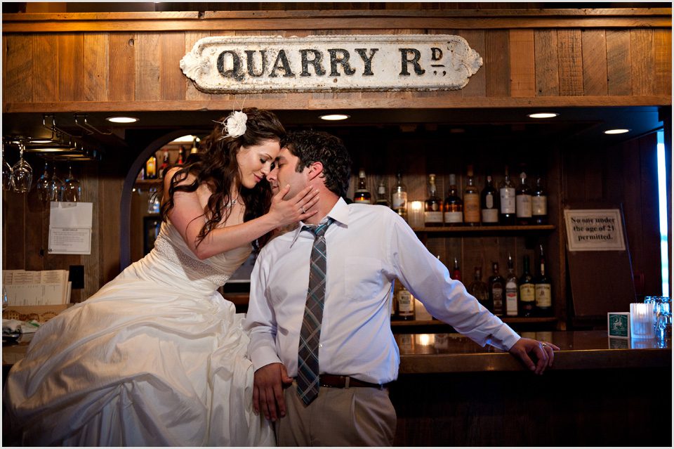 bride sits on bar and has a romantic moment with groom