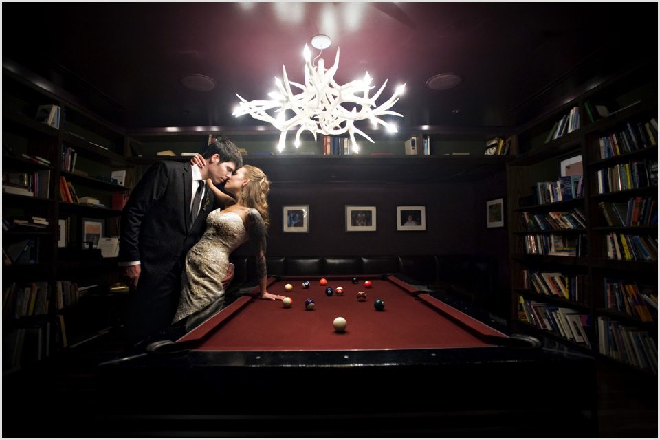 bride and groom with a pool table in the library at the nines hotel