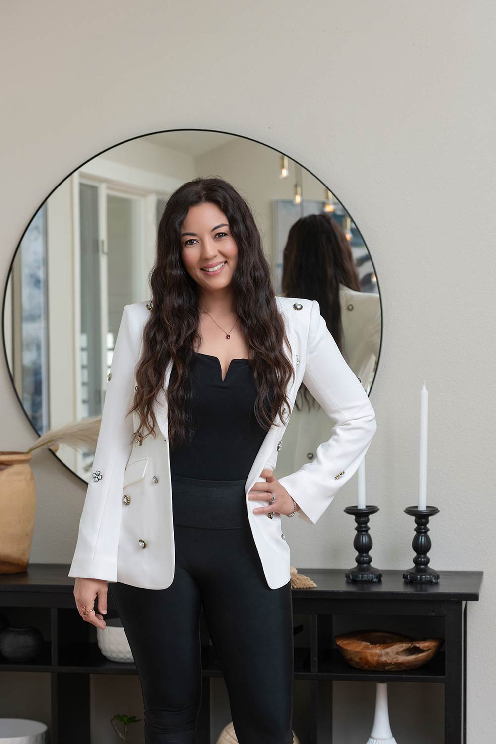 woman in white and black standing in front of a big round mirror