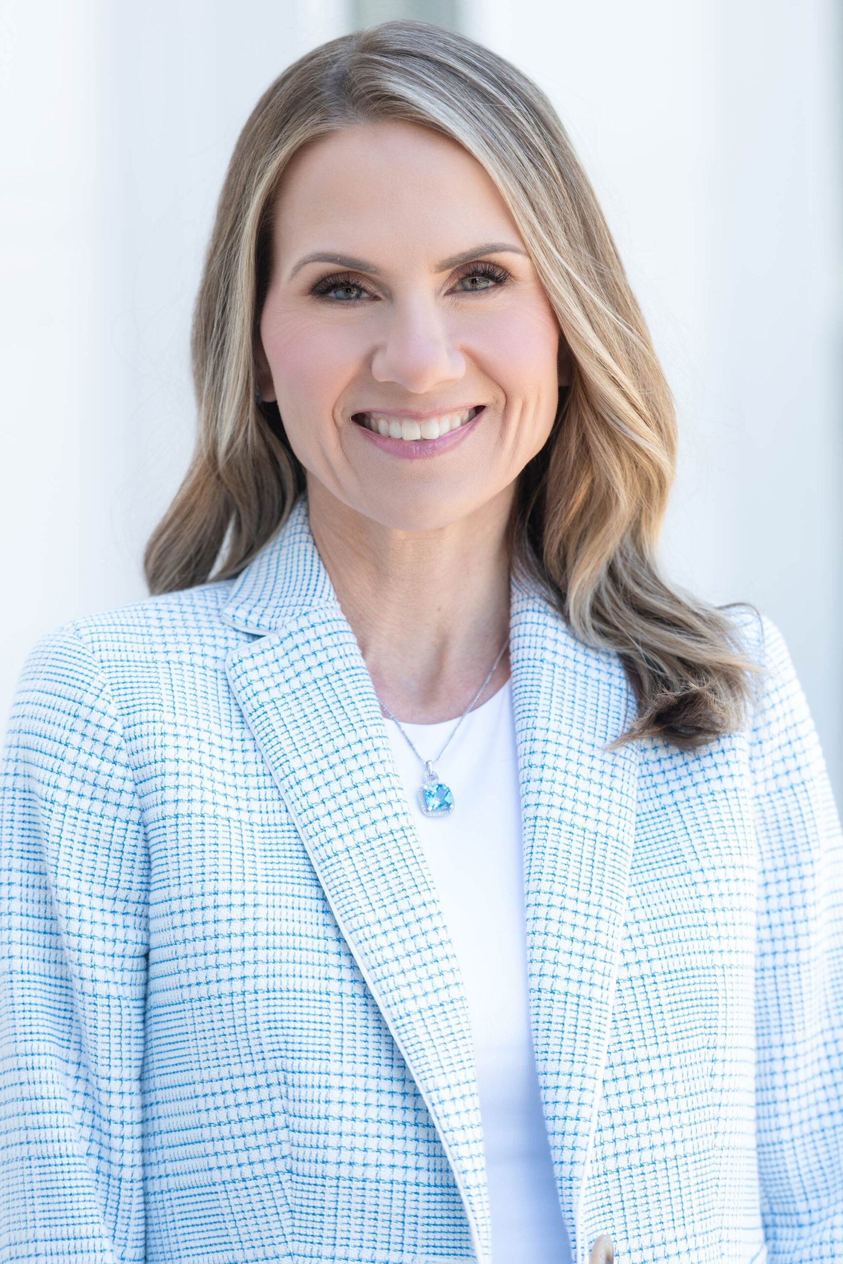 woman in a light blue business jacket against a white wall